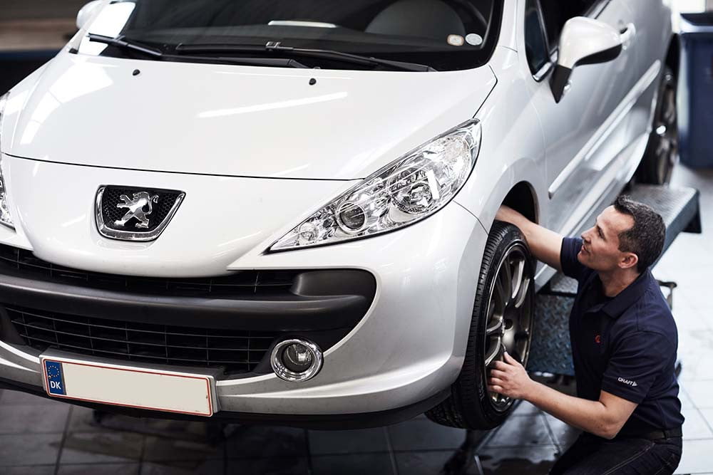 Mekaniker tjekker hjul på peugeot bil på værksted